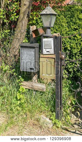 sunny illuminated scenery showing a garden gate with letter boxes doorbell and lamp