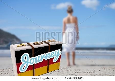 Blonde in white dress walking on the beach against suitcase with the german flag
