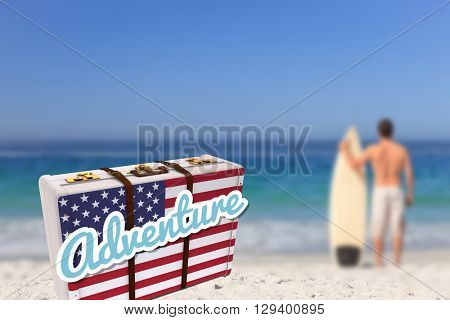 Suitcase with the American flag against man wirth his surfboard on the beach