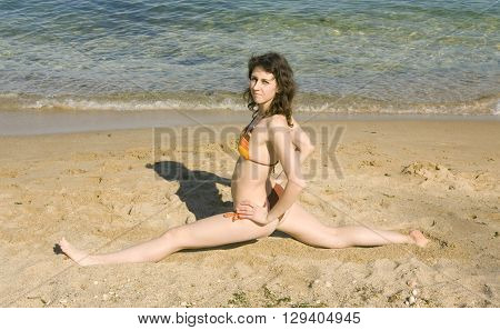 Young European woman making sport fitness exercies on beach 