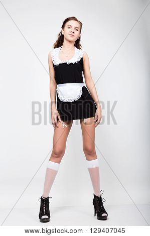 Beautiful young woman dressed as a sexy maid-servant in a skimpy uniform, posing provocatively.