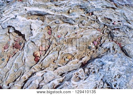 Portrait of a stone. Stone wavy texture with veins of quartz and small stones in the cracks.