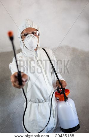 Portrait of manual worker holding crop spray against walll