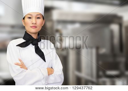 Portrait of confident female cook in kitchen against pots standing on hotplate