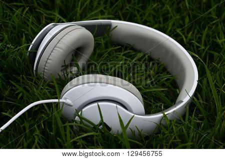 White big headphones on green spring grass