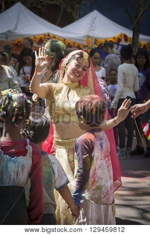 NEW YORK - APR 30 2016: A female member of NYC Bhangra dances with a group of young  children in the crowd at the Holi Hai Festival of Colors in Dag Hammerskjold Plaza in New York April 30, 2016.