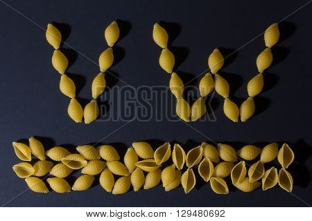 English alphabet laid out in the form of pasta shells on a dark background . VW/