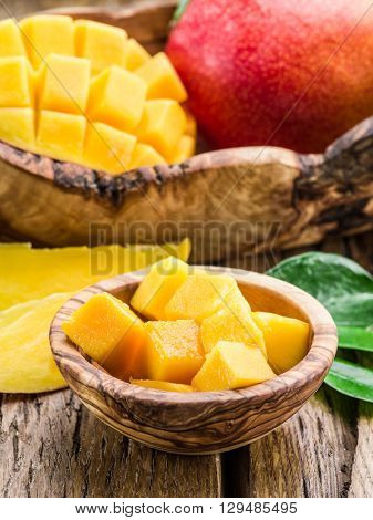 Mango fruit and mango cubes on the wooden table.