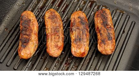 Freshly cooked pork sausages in a non stick griddle frying pan