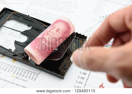 Rolled up scroll of CNY Chinese 100 yuan bill with portrait / image of Mao Zedong on a black rat trap. Using money as a bait to lure someone for illegal / dishonest things. China financial concept.