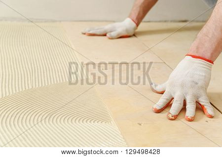Laying plywood on the floor. The worker put a piece of plywood on the floor with glue.