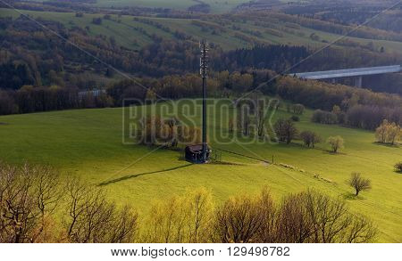 Transmitter on green meadow near highway to Germany
