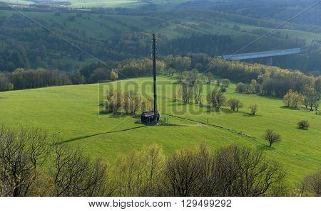 Transmitter on green meadow near highway to Germany