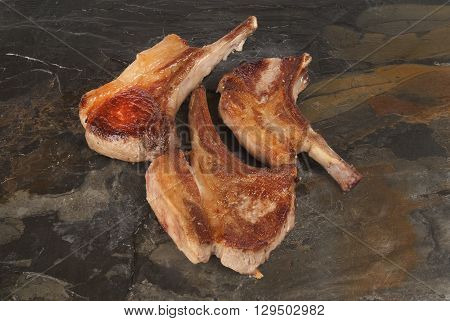 Freshly cooked pork chops against grey slate