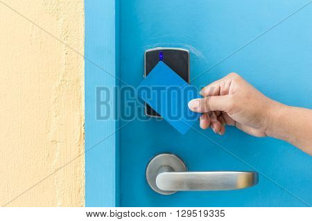 Hand Holding Blue Hotel Keycard In Front Of Electric Door