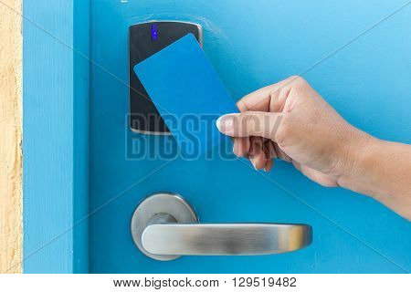 Hand Holding Blue Hotel Keycard In Front Of Electric Door