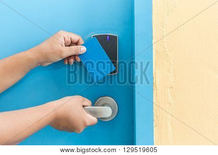 Hand Holding Blue Hotel Keycard In Front Of Electric Door