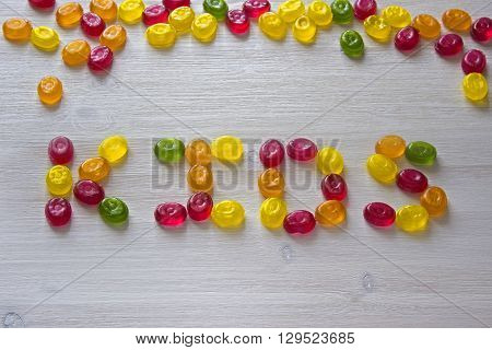 kids word made from candies on white wooden background