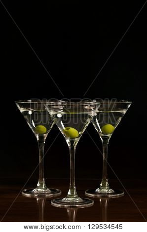 hree glasses of martini cocktail on a black background