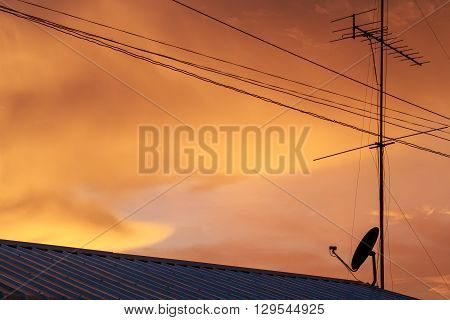television antenna and satellite dish silhouette in sunset sky