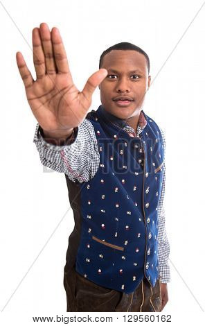 Stop says one isolated black man with his hand isolated over white background wearing typical bavarian clothes.