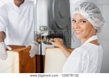 Confident Female Baker Using Cutting Machine In Bakery