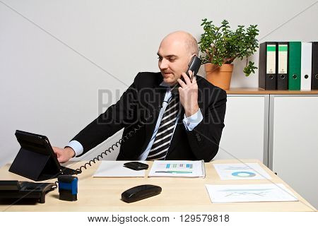 Manager On The Phone While He Compares Data On The Tablet
