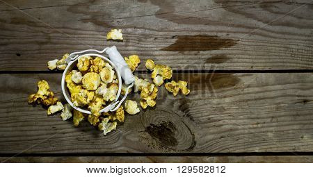 White bucket with popcorn on wooden background