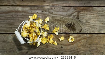 White bucket with popcorn on wooden background