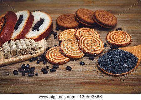 There are Pieces of Roll with Poppyseed,Cookies,Halavah Chocolate Peas,Tasty Sweet  Food on the Wooden Background,Toned
