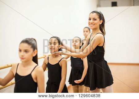 Portrait of a cute young Hispanic woman teaching little girls how to dance in a dance academy
