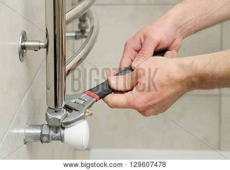 Plumber sets valve for towel warmer. It uses an adjustable wrench.