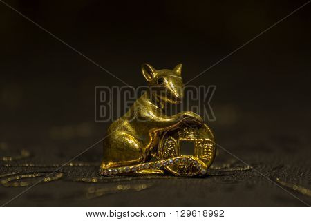 Mouse keeps coin Feng Shui for wealth on dark background