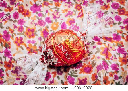 KILCHBERG SWITZERLAND - MARCH 20 2014: Beautiful Lindt Lindor chocolate truffle on a red luxury silk background. Lindt is one one of the lastgest luxury chocolate and confectionery company worldwide with more than 30 factories worldwide