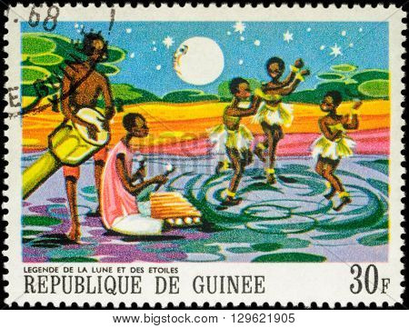 MOSCOW RUSSIA - MAY 12 2016: A stamp printed in Guinea shows three dancing black girls - scene from Legend of the moon and the stars series 