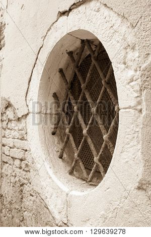 old brick facade of the ancient building with a round window and a iron lattice in retro style