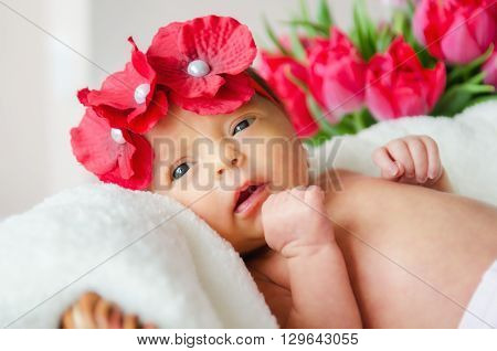 A baby girl in a red flower chaplet