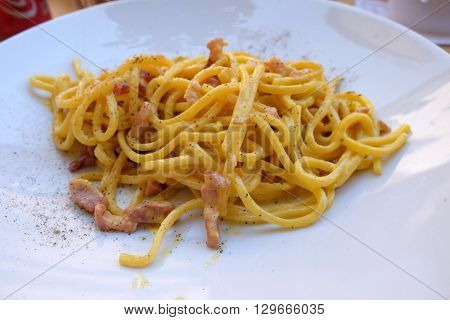 LUCCA, ITALY - JUNE 06, 2015: A classic pasta carbonara served outside in a pizzaria restaurant in Lucca, Italy, on June 06, 2015