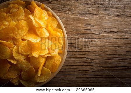 Flavored potato crisps in wooden bowl on table