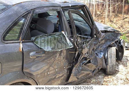 A wrecked car lays in wait after a vicious car accident. Rescue workers linger in the background.