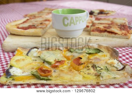 handcraft vegetarian pizza with near a cup of cappuccino