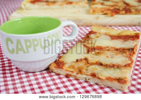 handcraft margherita pizza with near a cup of cappuccino