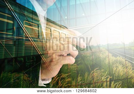 Double Exposure of Businessman writing Glass decorated Building and Train on Rural Scene with sunrise as Conceptual image