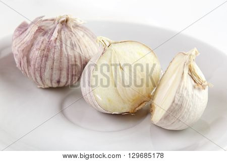 Single clove garlics on white dish whole and halves