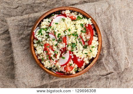 Homemade Fresh Couscous salad with vegetables wooden bowl. background