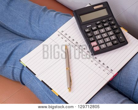 Blank notebook pen and calculator put on woman leg (Business Concept)