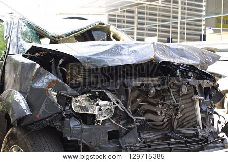 A wrecked car lays in wait after a vicious car accident. Rescue workers linger in the background.