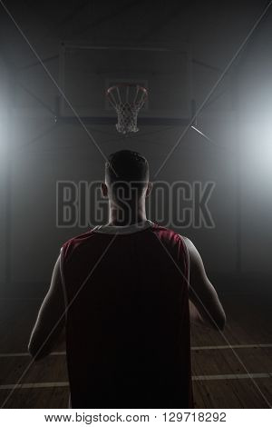 Portrait of basketball player front the back in front of a basket on a gym