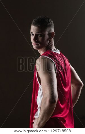 Portrait of basketball player front the back posing and looking the camera on a gym