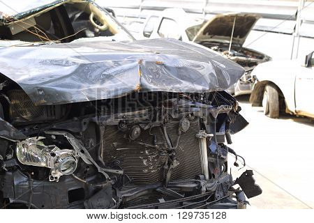 A wrecked car lays in wait after a vicious car accident. Rescue workers linger in the background.